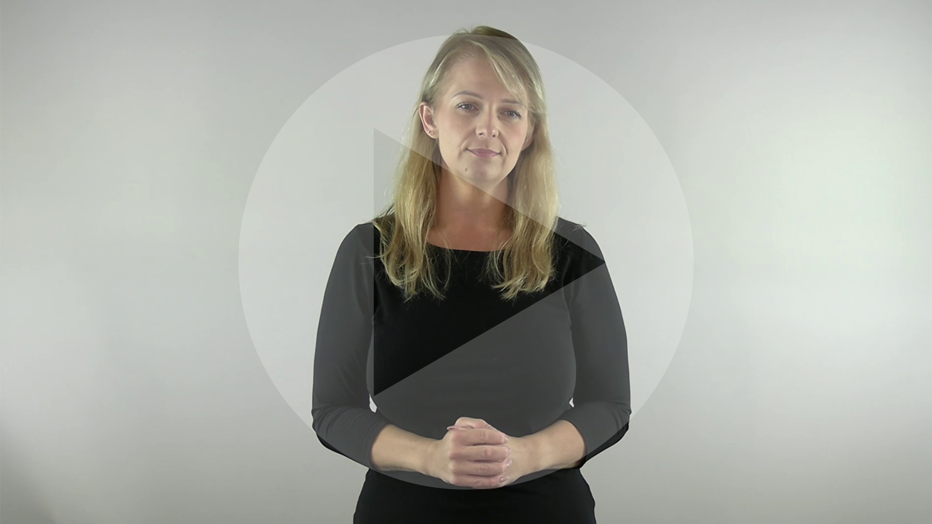 Kadr z nagrania przedstawiający tłumaczkę języka migowego. Na kadr naniesiony jest symbol odtwarzania wideo - trójkąt w kole