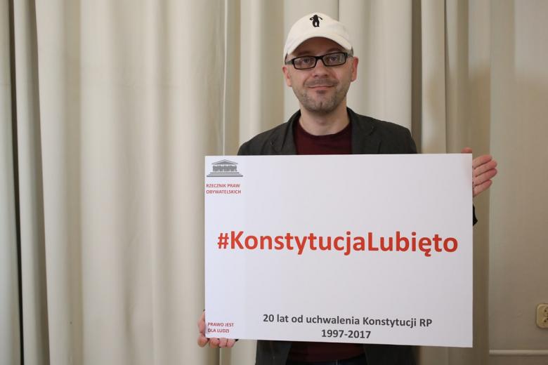 zdjęcie: mężczyzna stoi i trzyma planszę z napisem: Konstytucja lubię to