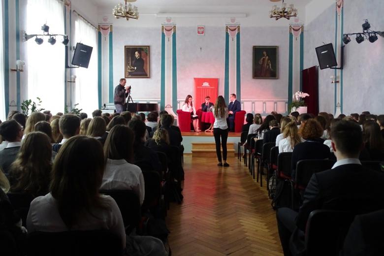 Aula szkolna, na podium uczniowie i Adam Bodnar