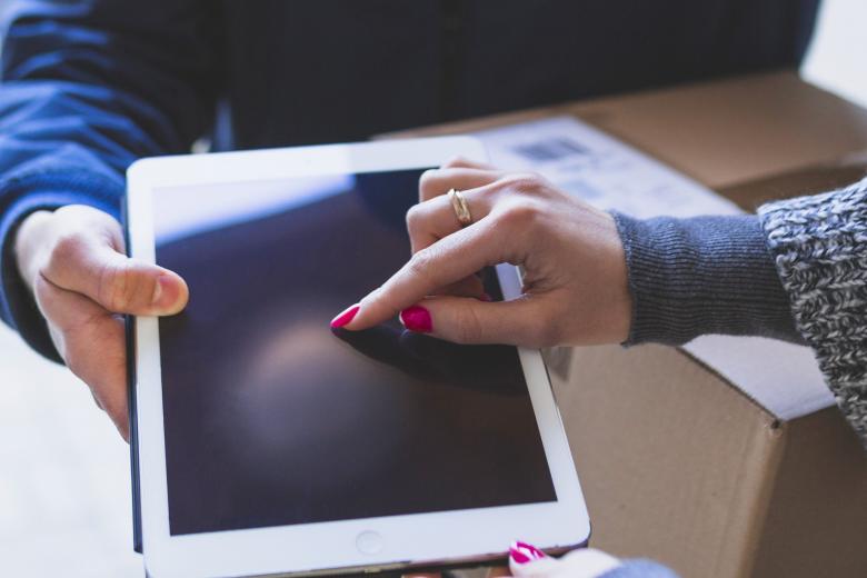 dłoń kobiety podpisującej się na tablecie