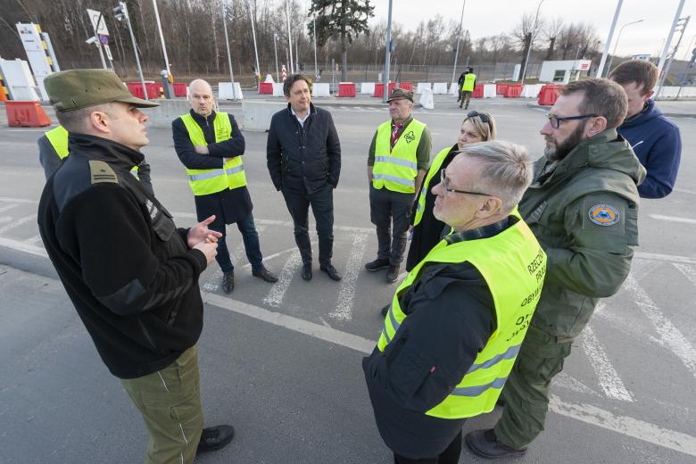 Pracownicy Biura RPO i funkcjonariusze Straży granicznej rozmawiają stojąc w kółku na wybetonowanym parkingu.