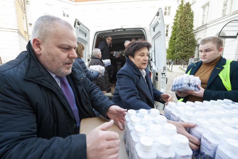 Pracownicy BRPO oraz wolontariusze załadowują artykuły spożywcze do samochodów.