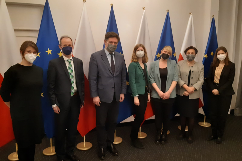 Ludzie stojący na tle flag Polski i Unii Europejskiej