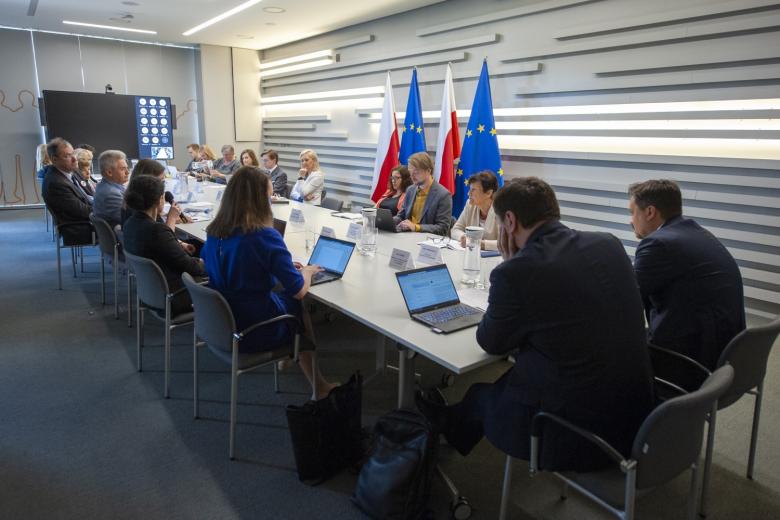 Kilkanaście osób siedzących przy stole w sali konferencyjnej