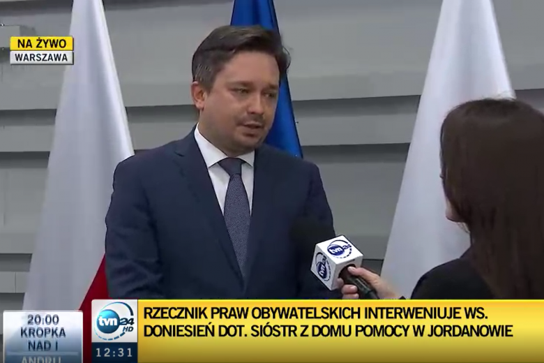 Zrzut ekranu przedstawiający mężczyznę udzielającego wypowiedzi do mikrofonu dziennikarki stacji telewizyjnej TVN24