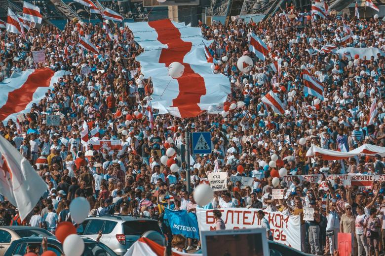 Tłum ludzi protestujących z biało-czerwono-białymi flagami