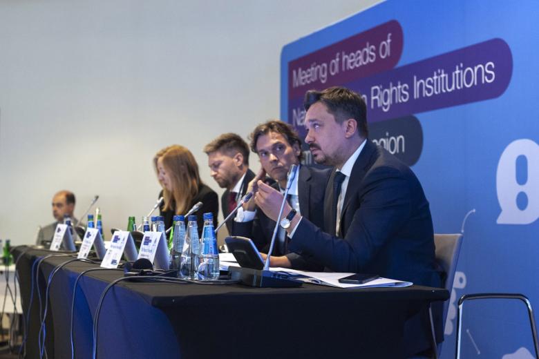 Grupa osób siedzących przy stole konferencyjnym. Na pierwszym planie przemawia RPO Marcin Wiącek