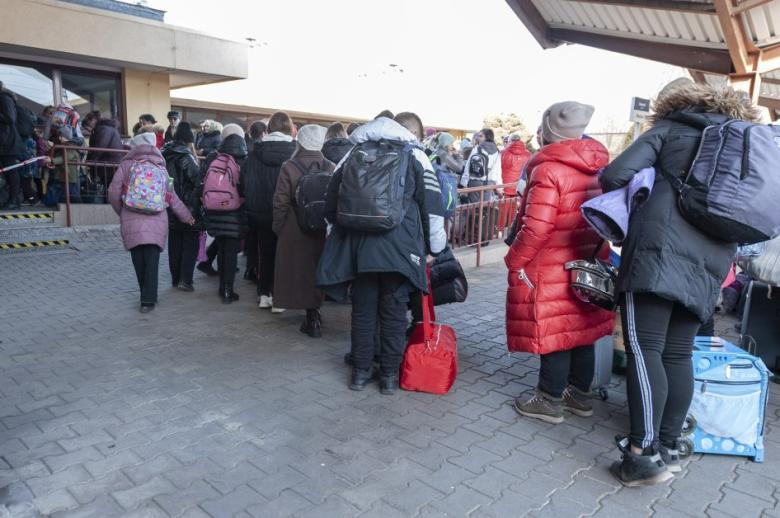 osoby z bagażami stoją w kolejce na dworcu 