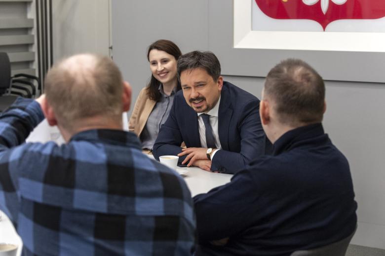 RPO Marcin Wiącek rozmawiający z osobami siedzącymi przy stole w sali konferencyjnej