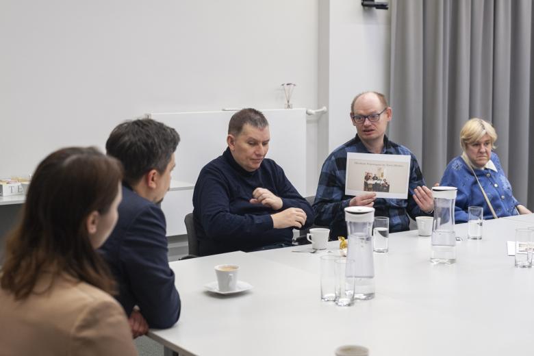 Mężczyzna siedzący za stołem pokazuje kartkę ze zdjęciem Rzecznikowi Praw Obywatelskich