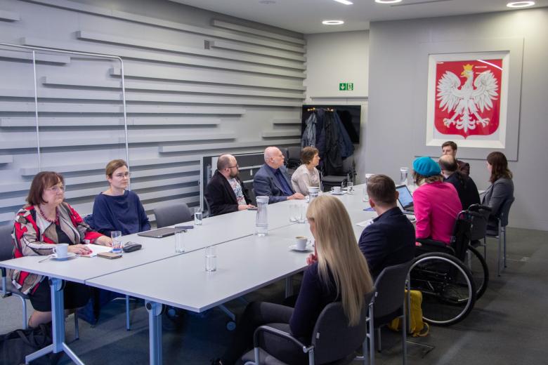 Grupa kilkunastu osób siedząca przy stole konferencyjnym