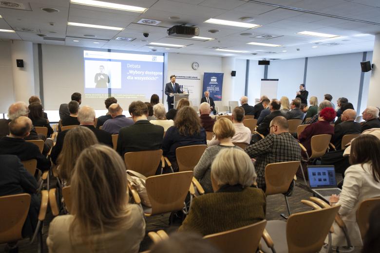 Marcin Wiącek wypowiada się z podium w sali konferencyjnej