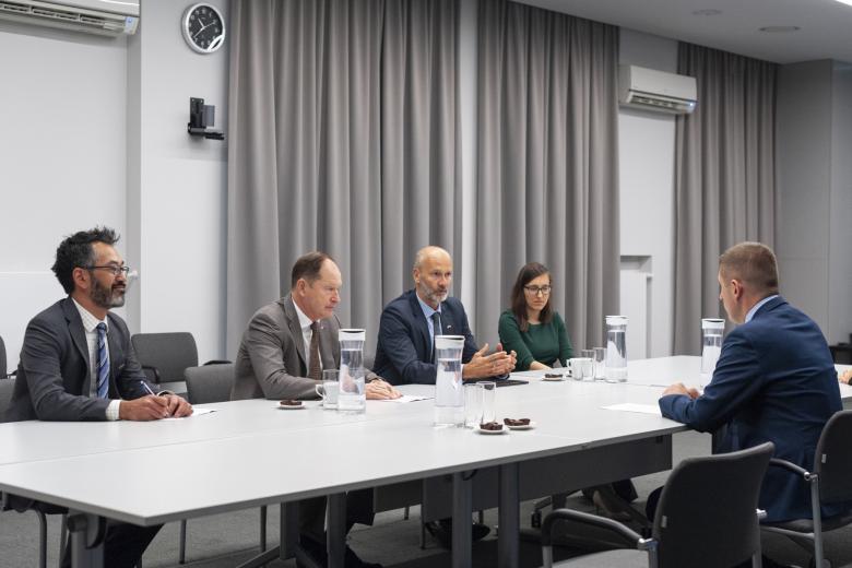 Sześć osób siedzi po dwóch stronach dużego stołu w sali konferencyjnej