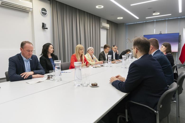 Grupa osób siedzi przy dużym prostokątnym stole