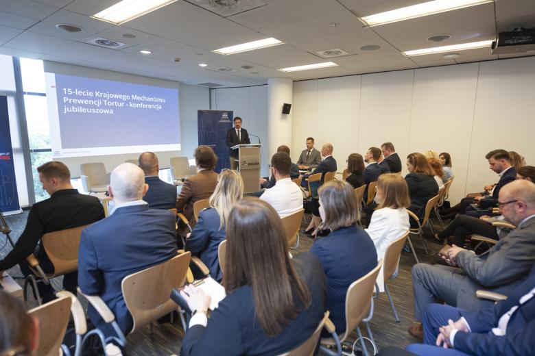 Kilkadziesiąt osób na sali konferencyjnej słucha wystąpienia RPO Marcina Wiącka