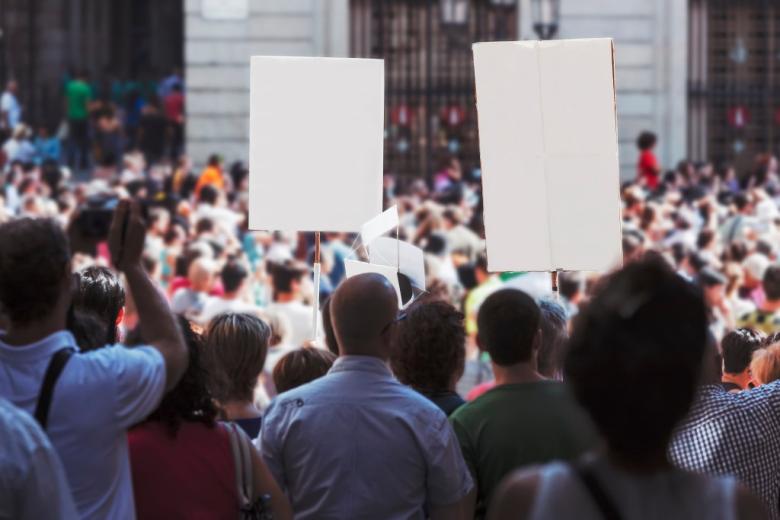   manifestanci  trzymają transparenty z niewidocznymi hasłami