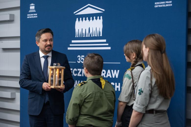 Troje harcerzy wręcza Marcinowi Wiąckowi zapaloną świecę