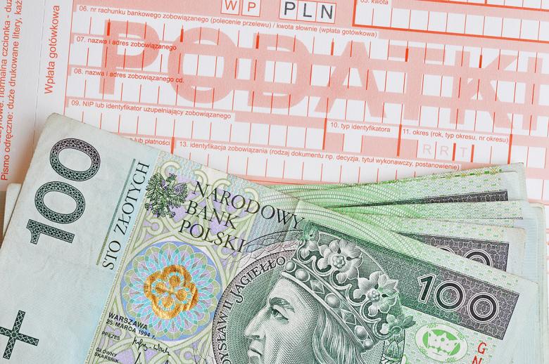 Plik banknotów stuzłotowych leżący na druku podatkowym