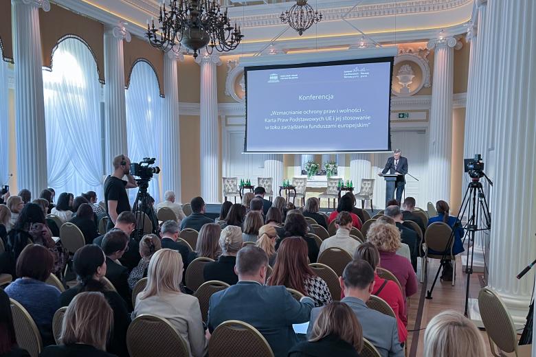 Sala konferencyjna wypełniona ludźmi. Na podium wypowiada się Stanisław Trociuk