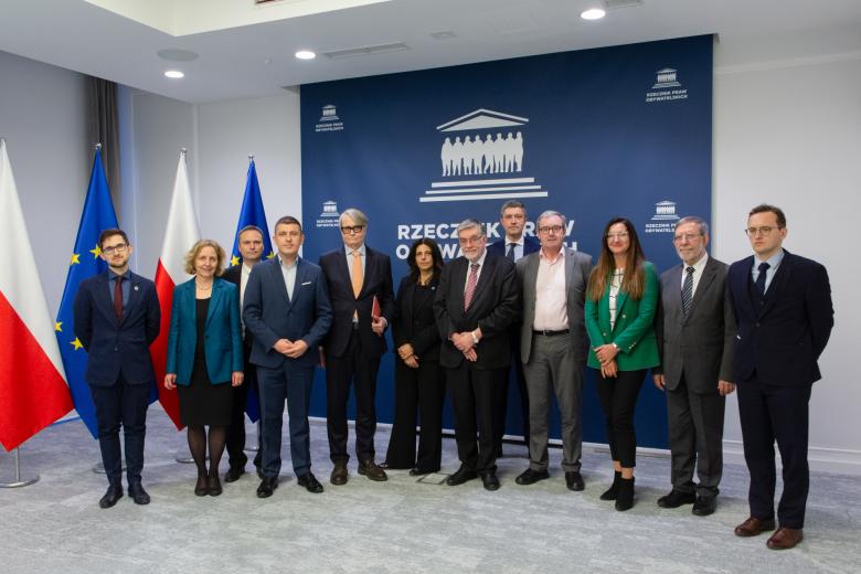 Dwanaście osób pozuje do wspólnego zdjęcia na stojąco