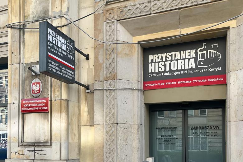 Szyld centrum edukacyjnego IPN "Przystanek Historia". Obok wejścia do lokalu wiszą tabliczki urzędowe z godłem Polski i podpisem "Instytut Pamięci Narodowej - Komisja Ścigania Zbrodni Przeciwko Narodowi Polskiemu"