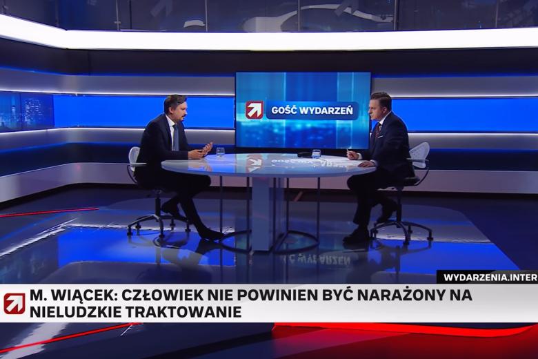 Zrzut ekranu programu telewizyjnego przedstawiający dwie osoby siedzące w studiu telewizyjnym i rozmawiające