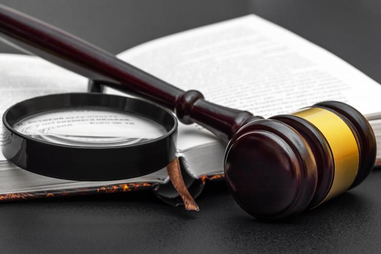 Lupa i sędziowski młotek ułożone na otwartej książce