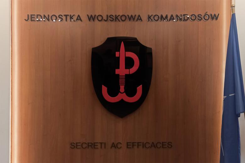 Ściana z symbolem jednostki wojskowej, obok której stoi flaga NATO