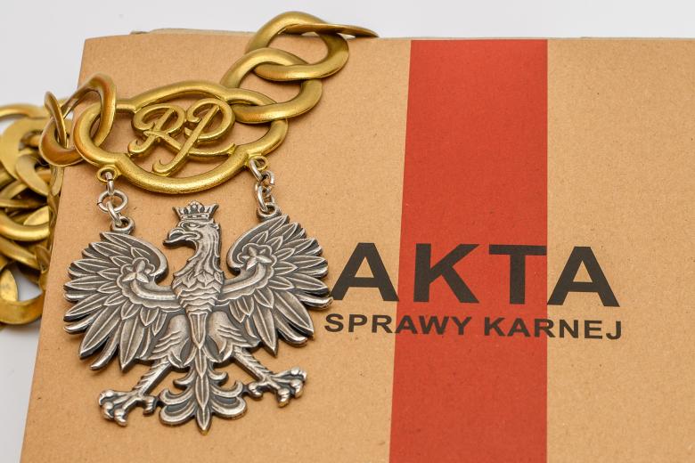 Łańcuch sędziowski leży na teczce z aktami sprawy karnej