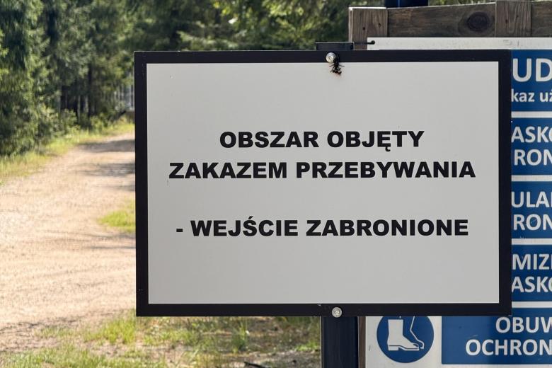 Prostokątny znak z napisem "Obszar objęty zakazem przebywania - wejście zabronione"