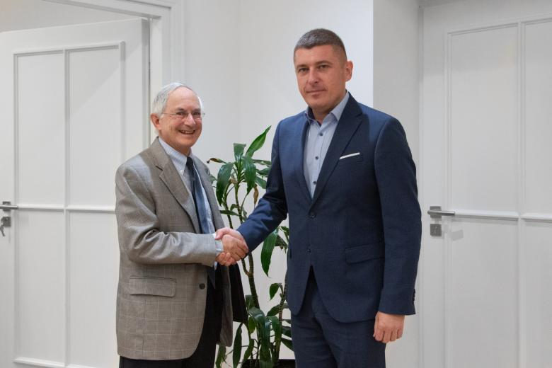 Dwie osoby pozują do zdjęcia ściskając dłonie na powitanie