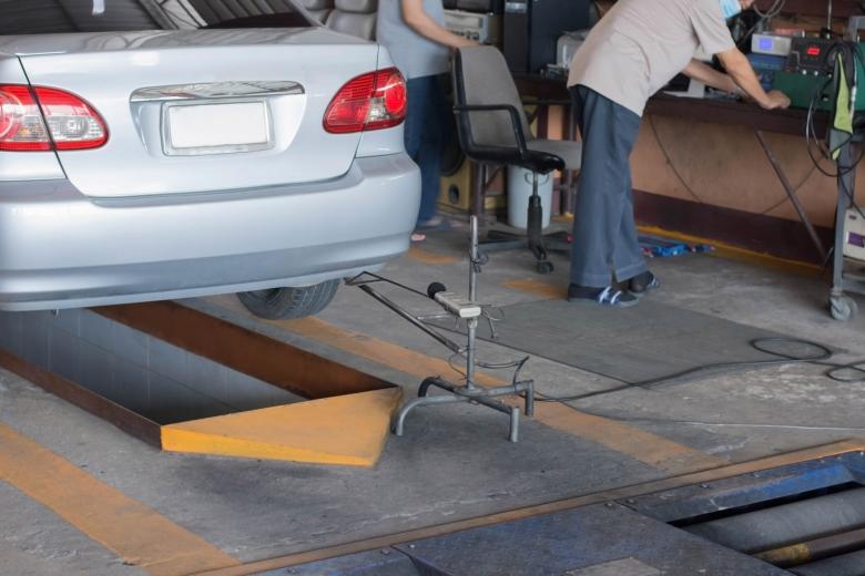 Samochód w stacji diagnostycznej z czujnikiem hałasu ustawionym przy rurze wydechowej