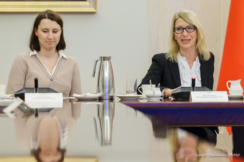 Dwie osoby siedzą obok siebie przy stole 