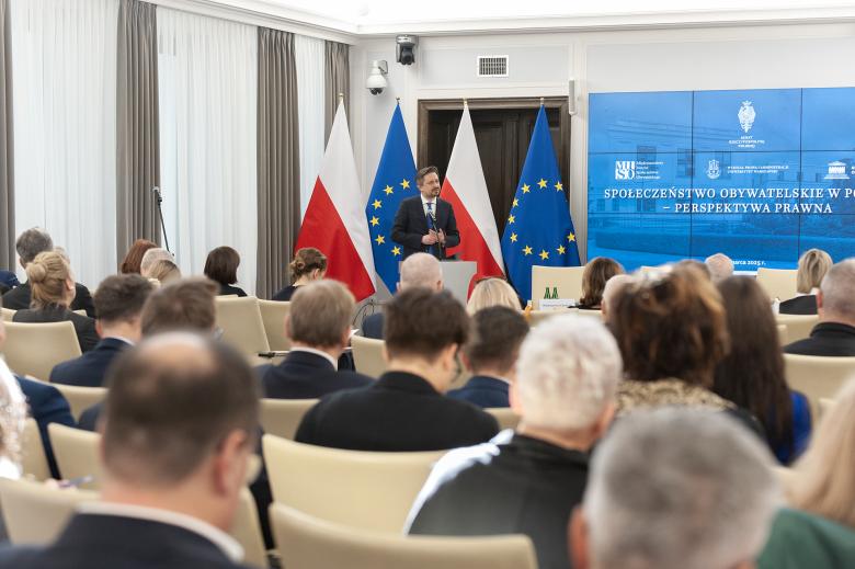 Osoba przemawia za mównicą na sali konferencyjnej