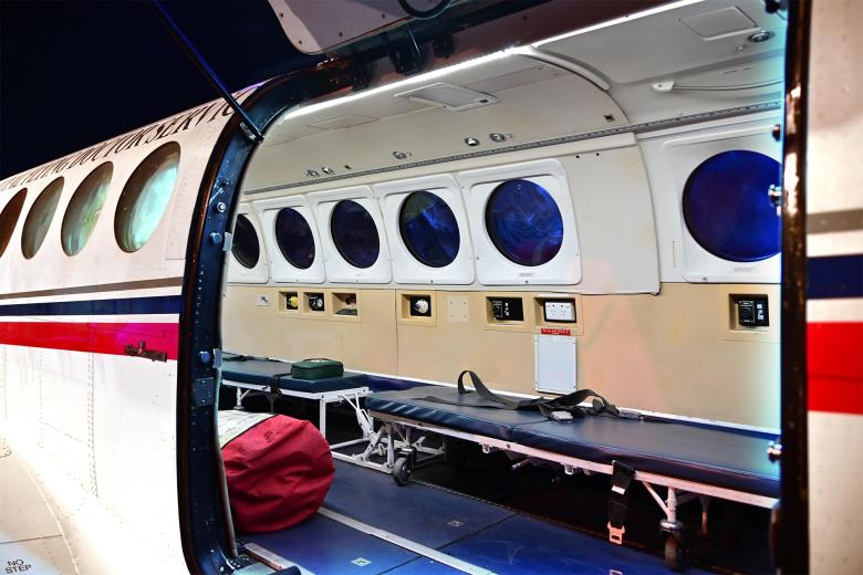 Otwarty właz samolotu, w środku którego znajduje sie kilka łóżek do transportu pacjentów