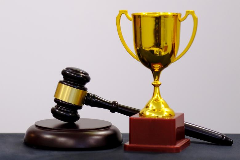 Trofeum sportowe i młotek sędziowski stoją obok siebie na blacie
