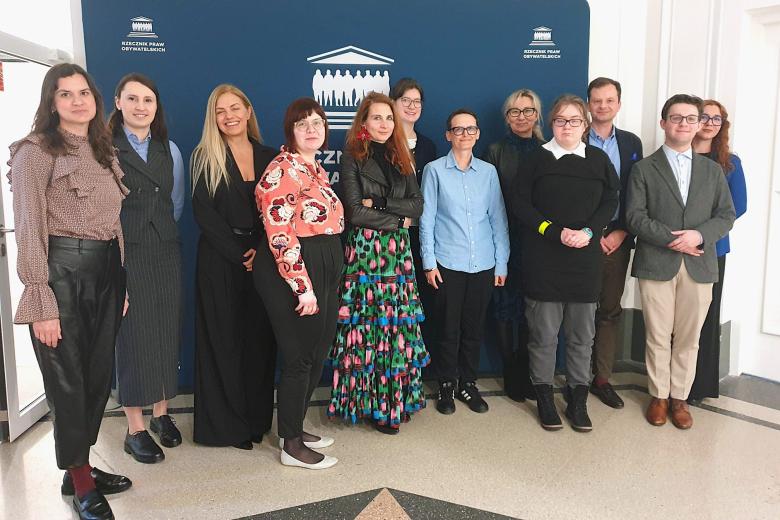 Kilkanaście osób pozuje na stojąco do wspólnego zdjęcia