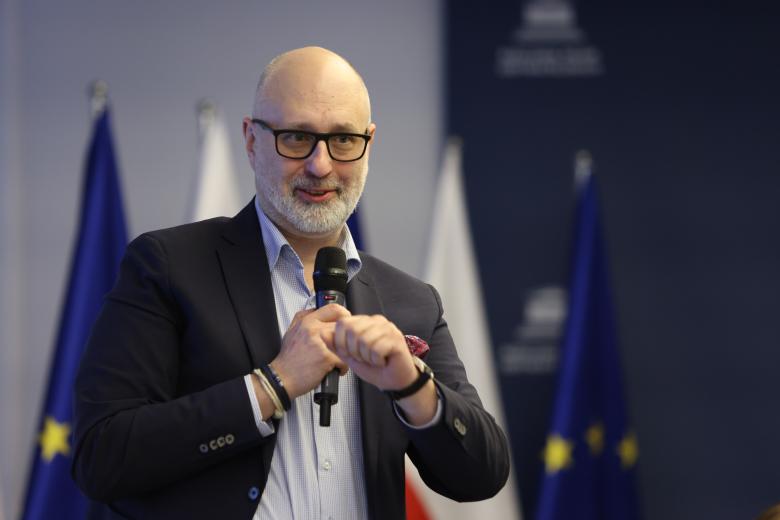 Mężczyzna wypowiada się do mikrofonu, gestykulując. 