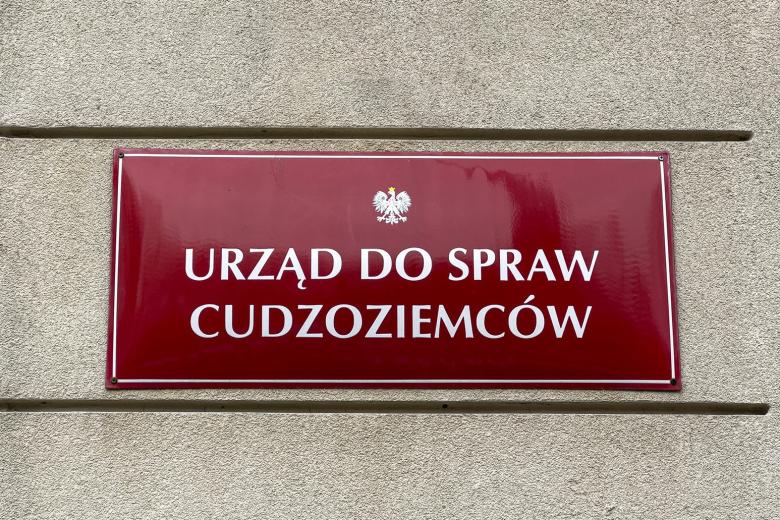 Przykręcona do elewacji budynku tablica z godłem Polski - orłem w koronie - i napisem "Urząd do spraw Cudzoziemców"