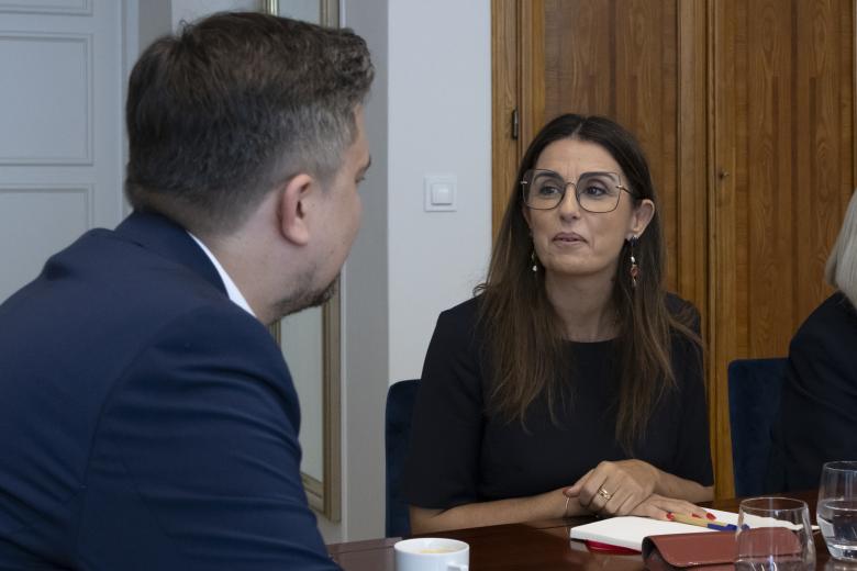 Marcin Wiącek i Teresa Anjinho rozmawiają siedząc przy stole konferencyjnym