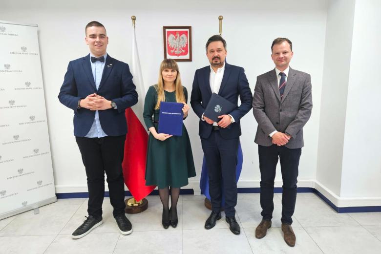 Cztery osoby pozują na stojąco do wspólnego zdjęcia