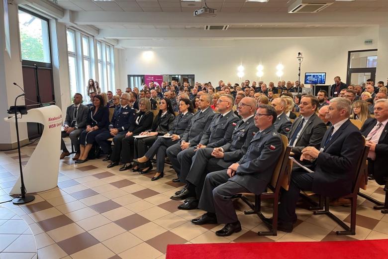 Zapełniona siedzącymi ludźmi aula.