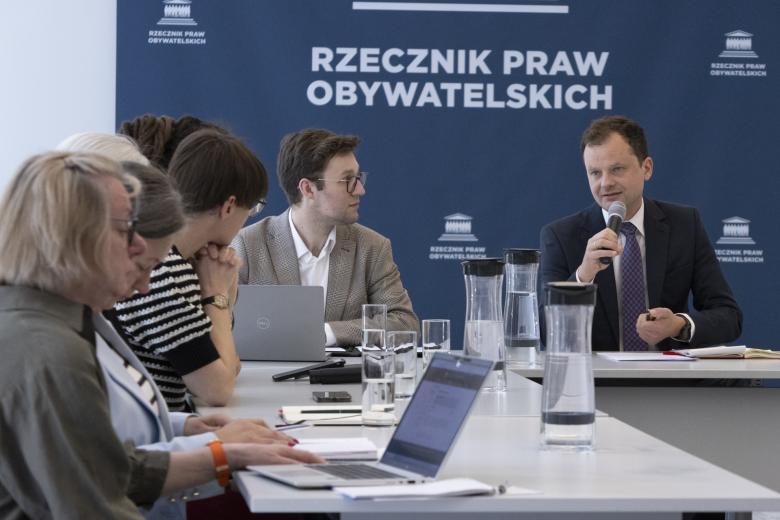 Osoby siedzące za stołem w sali konferencyjnej