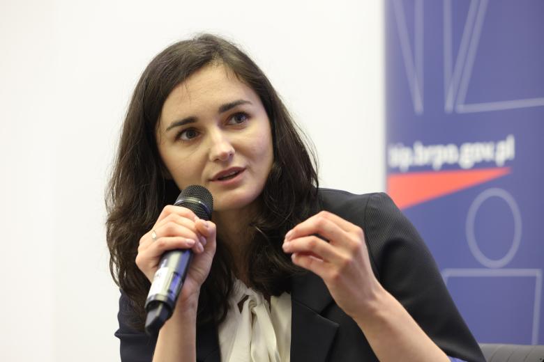 Anna Grochowska-Wasilewska wypowiada się trzymając w dłoni mikrofon i gestykulując