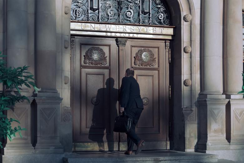 dwie osoby wchodzą do budynku z napisem rektorat uniwersytetu