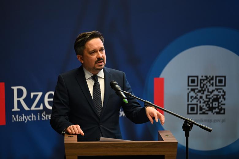 Rzecznik przemawia do mikrofonu za mównicą