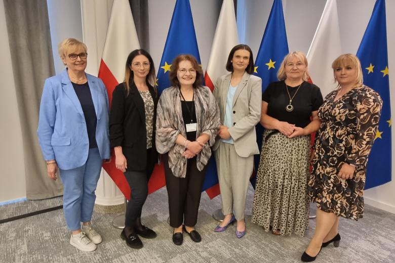 Sala konferencyjna, kobiety stojące na tle flag