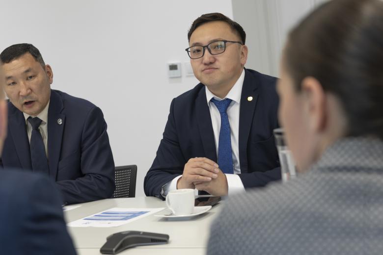 Cztery osoby rozmawiają przy stole konferencyjnym.