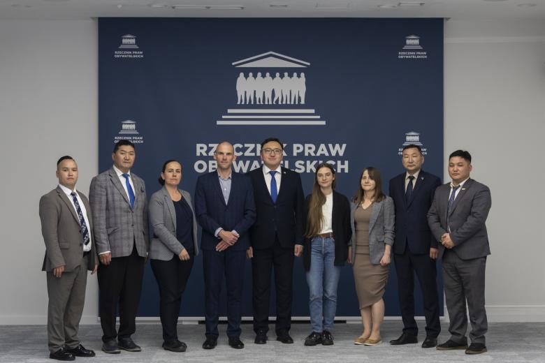 Dziewięć osób pozuje do zdjęcia na tle ścianki z logiem Rzecznika Praw Obywatelskich