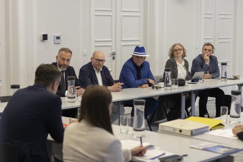 Osoby siedzące za stołem w sali konferencyjnej